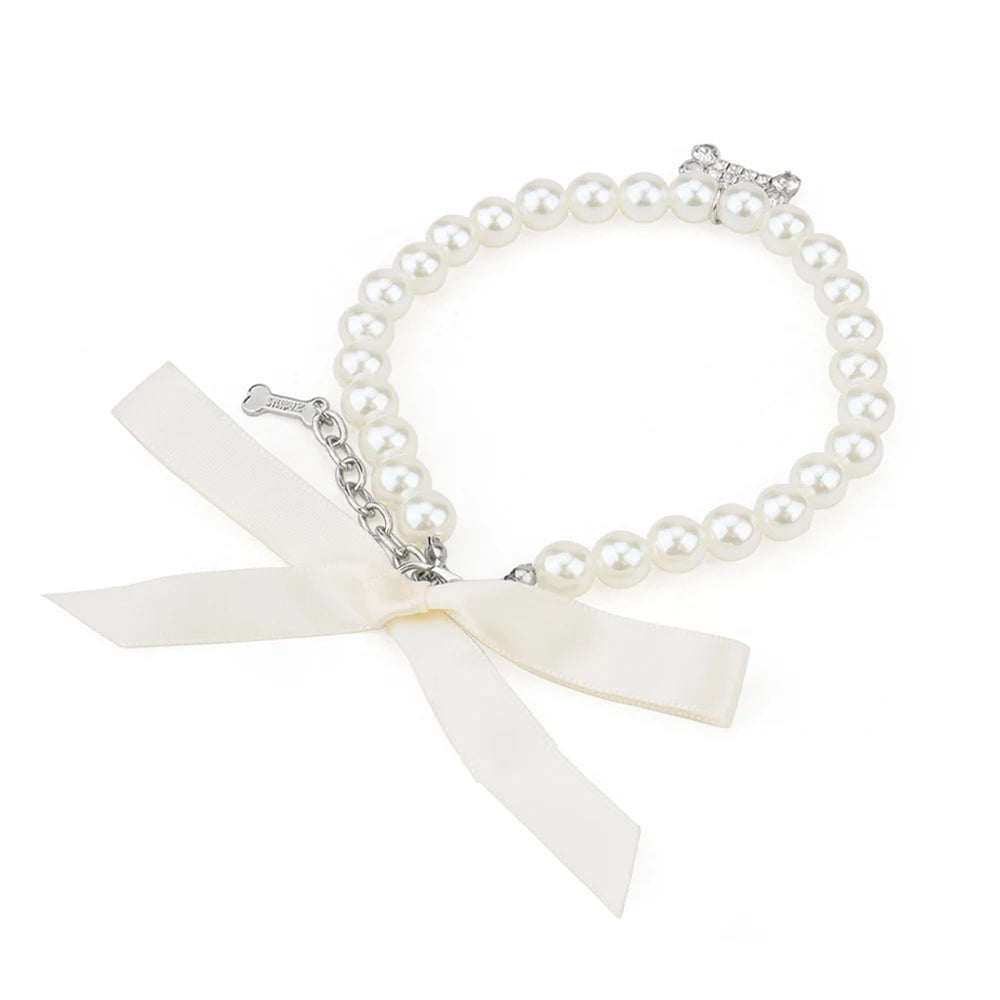 Vue haute d’un collier perlé blanc pour chien avec pendentif os brillant.