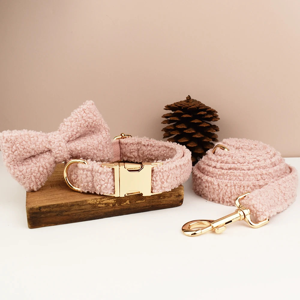 Ensemble collier, noeud papillon et laisse rose pâle pour chien en tissu bouclette présenté sur un support en bois.