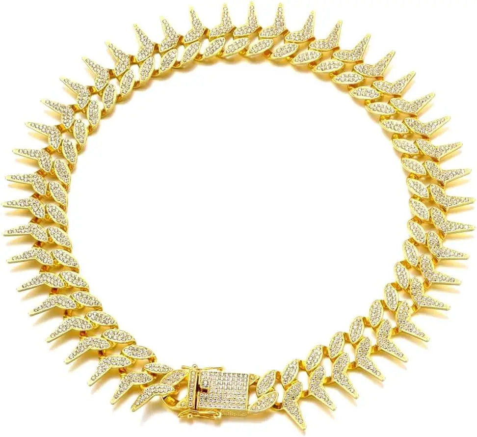Collier chaîne doré pour chien avec strass et pointes sur fond clair.