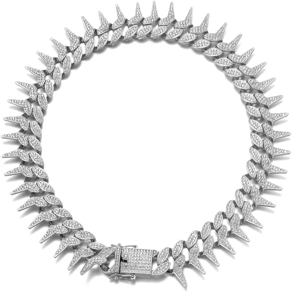 Collier chaîne argenté pour chien avec strass et pointes sur fond clair.