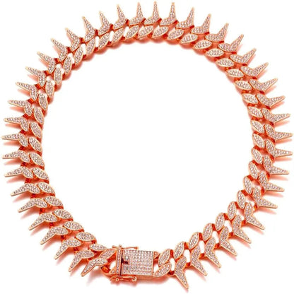 Collier chaîne rose doré pour chien avec strass et pointes sur fond clair.