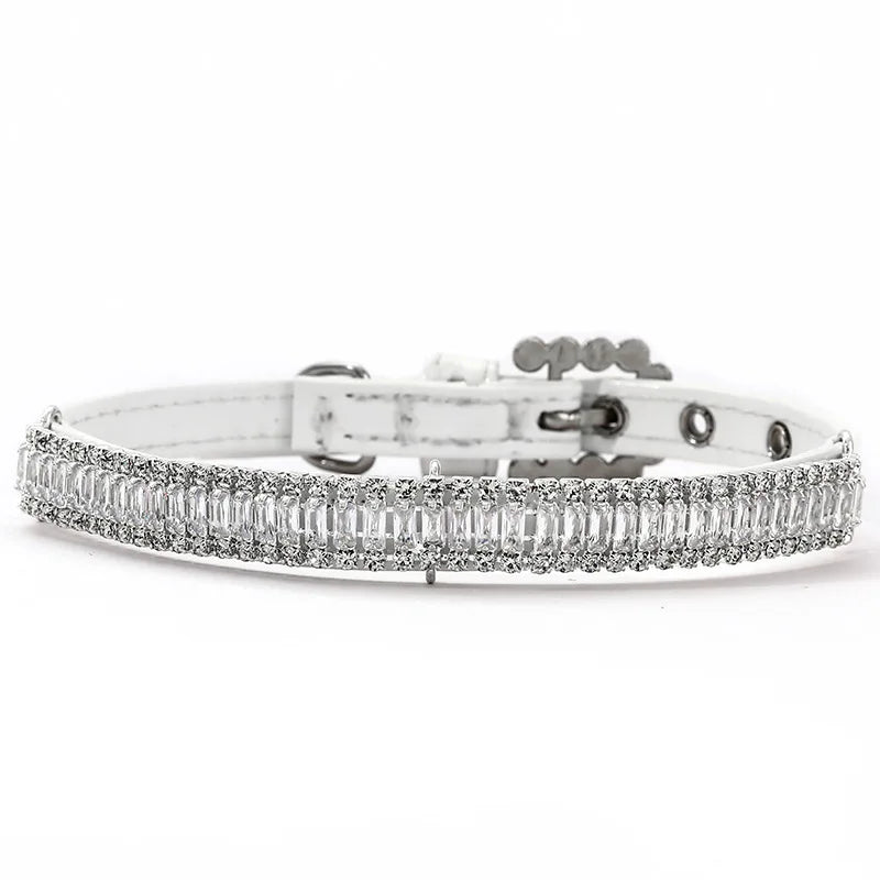 Collier blanc pour chien avec rangée centrale de strass sur fond clair.