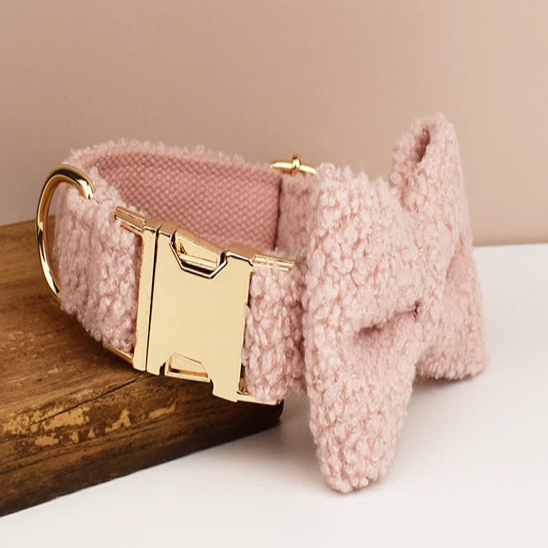 Collier rose pour chien en tissu bouclette avec nœud papillon vu de profil et présenté sur un support en bois.
