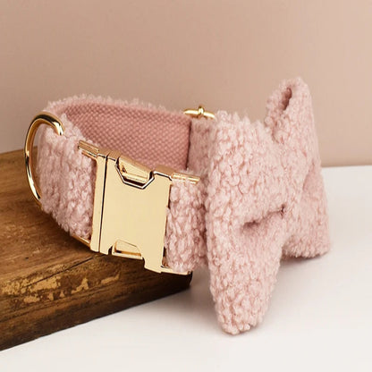 Collier rose pour chien en tissu bouclette avec nœud papillon vu de profil et présenté sur un support en bois.