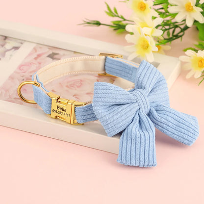 Vue du collier pour chien en coton doux bleu avec grand nœud papillon et plaque gravée personnalisée sur fond décoratif floral