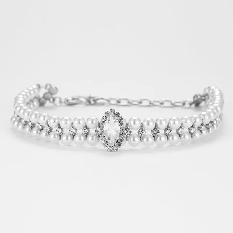 Collier pour chien avec rangées de perles blanches et pendentif central sur fond clair.
