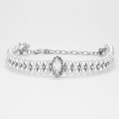 Collier pour chien avec rangées de perles blanches et pendentif central sur fond clair.