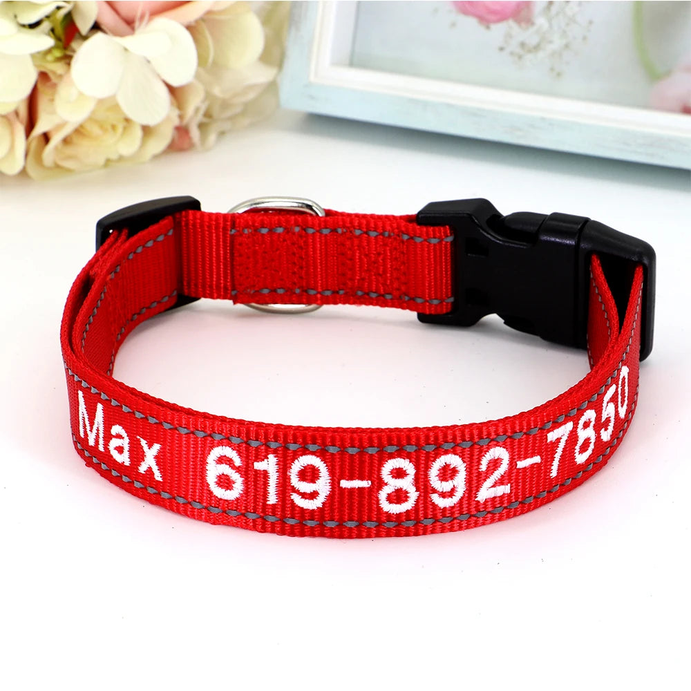 Collier pour chien en nylon rouge avec prénom et numéro de téléphone brodés en blanc, boucle à clip plastique noire et anneau en D argenté, posé sur fond rose clair.
