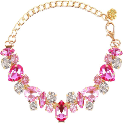 Collier pour chien avec pierres roses, strass et chaîne dorée sur fond clair.