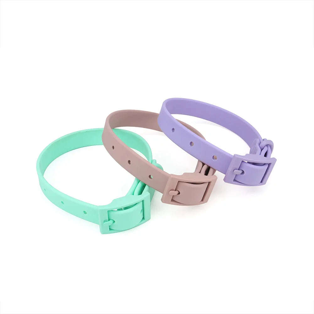 Trois colliers pour chien en PVC imitation silicone présentés en coloris menthe, taupe et lilas, avec boucle à ardillon rectangulaire intégrée de même couleur et trous de réglage visibles sur fond blanc.