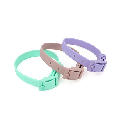 Trois colliers pour chien en PVC imitation silicone présentés en coloris menthe, taupe et lilas, avec boucle à ardillon rectangulaire intégrée de même couleur et trous de réglage visibles sur fond blanc.