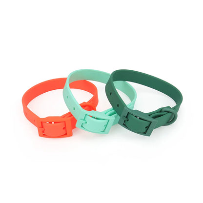 Trois colliers pour chien en PVC imitation silicone présentés côte à côte en coloris orange vif, menthe et vert forêt, avec boucle à ardillon rectangulaire intégrée de même couleur et trous de réglage visibles sur fond blanc.