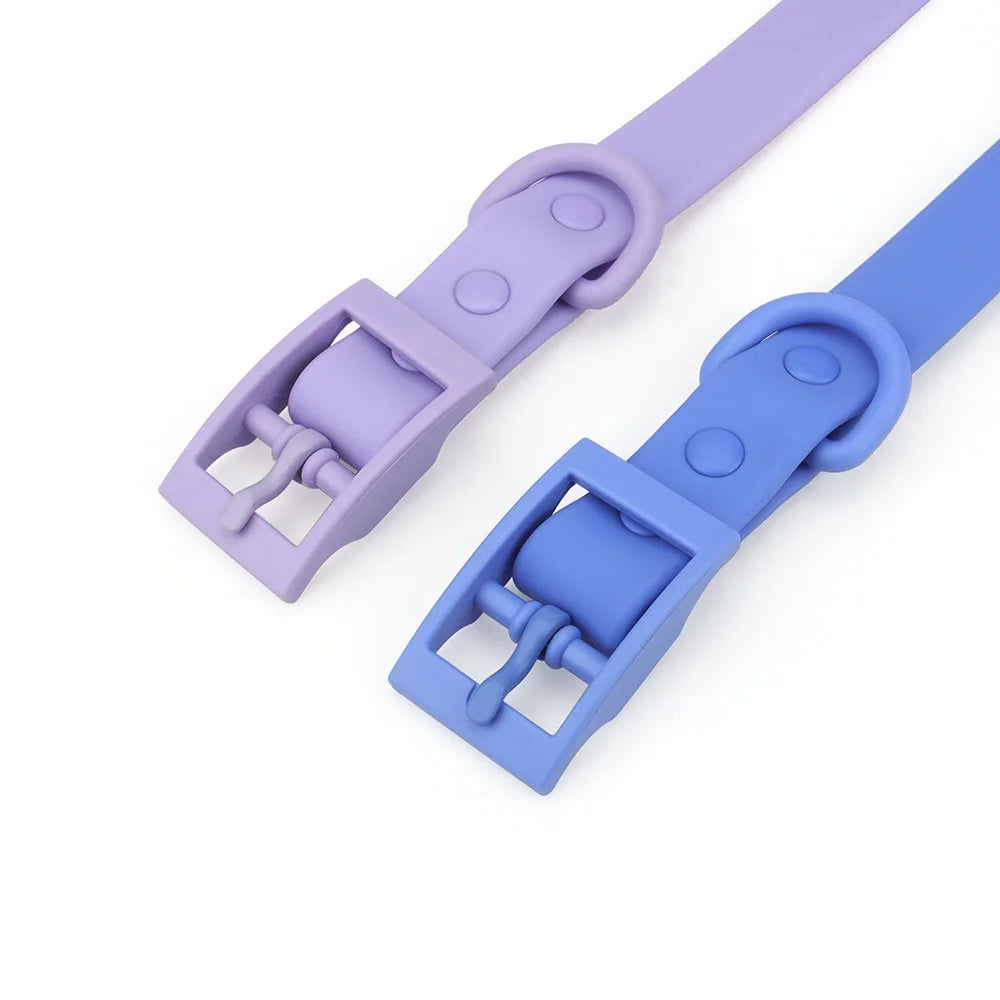 Gros plan sur la boucle à ardillon rectangulaire de deux colliers chien en PVC imitation silicone, coloris lilas et bleu, montrant l'ardillon, le passant et l'anneau en D intégrés de même couleur.