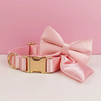 Collier rose pour chien avec grand nœud détachable et anneau métal doré présenté devant un fond rose et blanc.