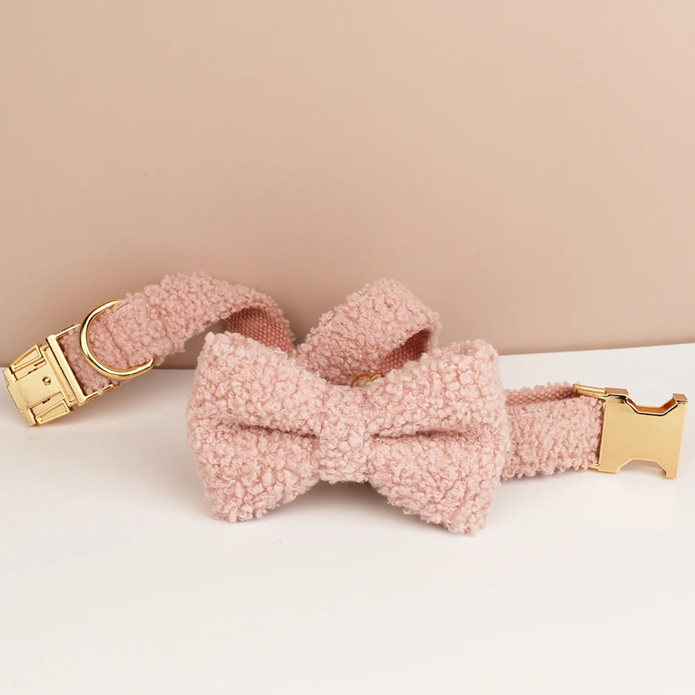 Collier chien bouclette rose avec boucle métal dorée enroulé sur fond rose et blanc.