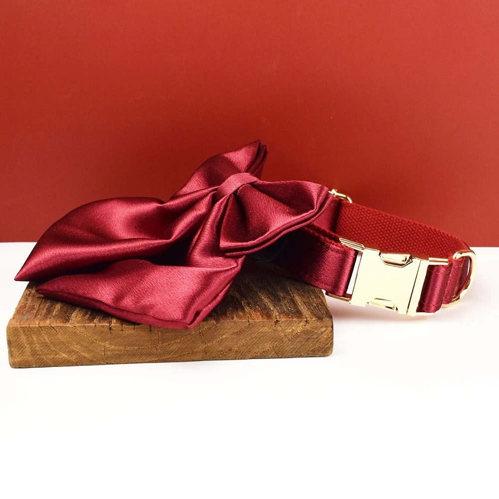 Collier rouge pour chien avec grand nœud détachable et anneau métal doré présenté sur un support en bois.