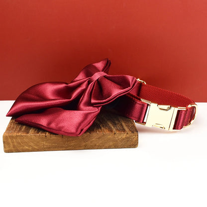 Collier rouge pour chien avec grand nœud détachable et anneau métal doré présenté sur un support en bois.