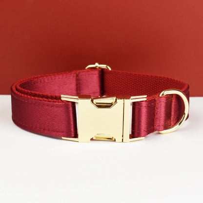 Collier rouge pour chien avec boucle métal dorée gravée devant un fond rouge et blanc.