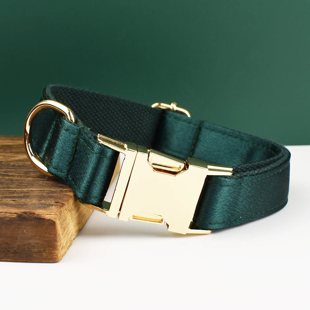 Collier vert foncé pour chien avec boucle métal dorée gravée présenté sur un support en bois.