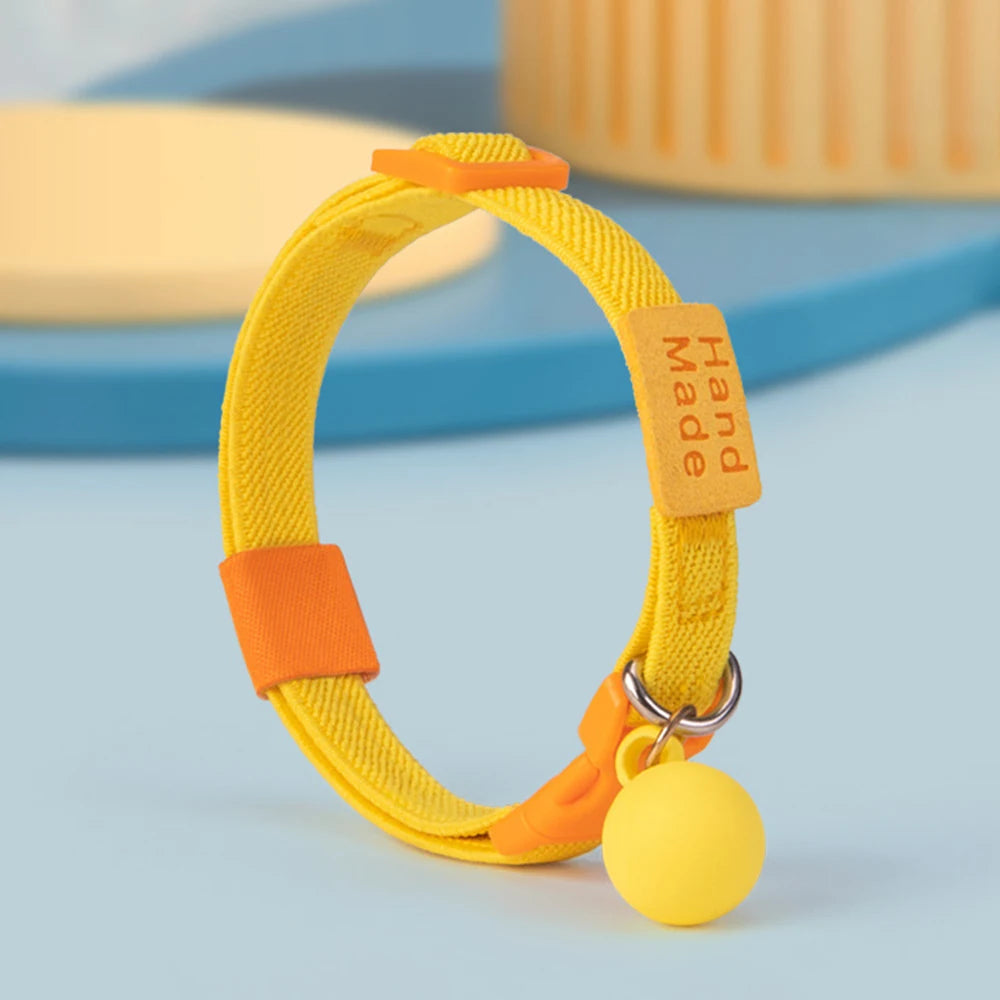 Collier jaune pour chiot présenté debout avec boule décorative jaune sur fond coloré.