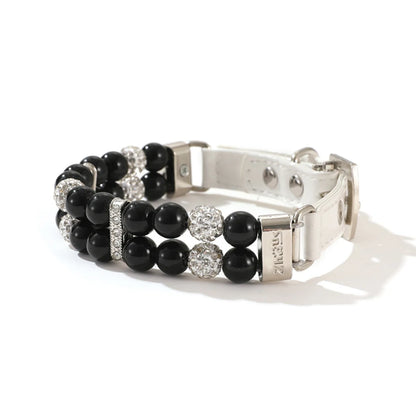 Collier de luxe pour chien à double rang de perles noires avec strass scintillants sur fond clair.