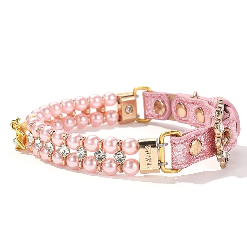 Vue de trois quarts d’un collier de luxe pour chien rose avec perles artificielles et pendentif en cristal.