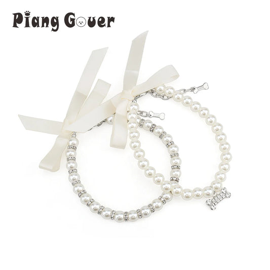 Deux colliers bijou pour chien en perles blanches avec ruban et pendentif os décoratif.