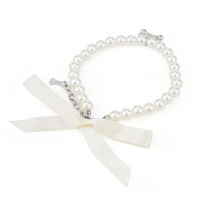 Vue haute d’un collier perlé blanc pour chien avec pendentif os brillant.