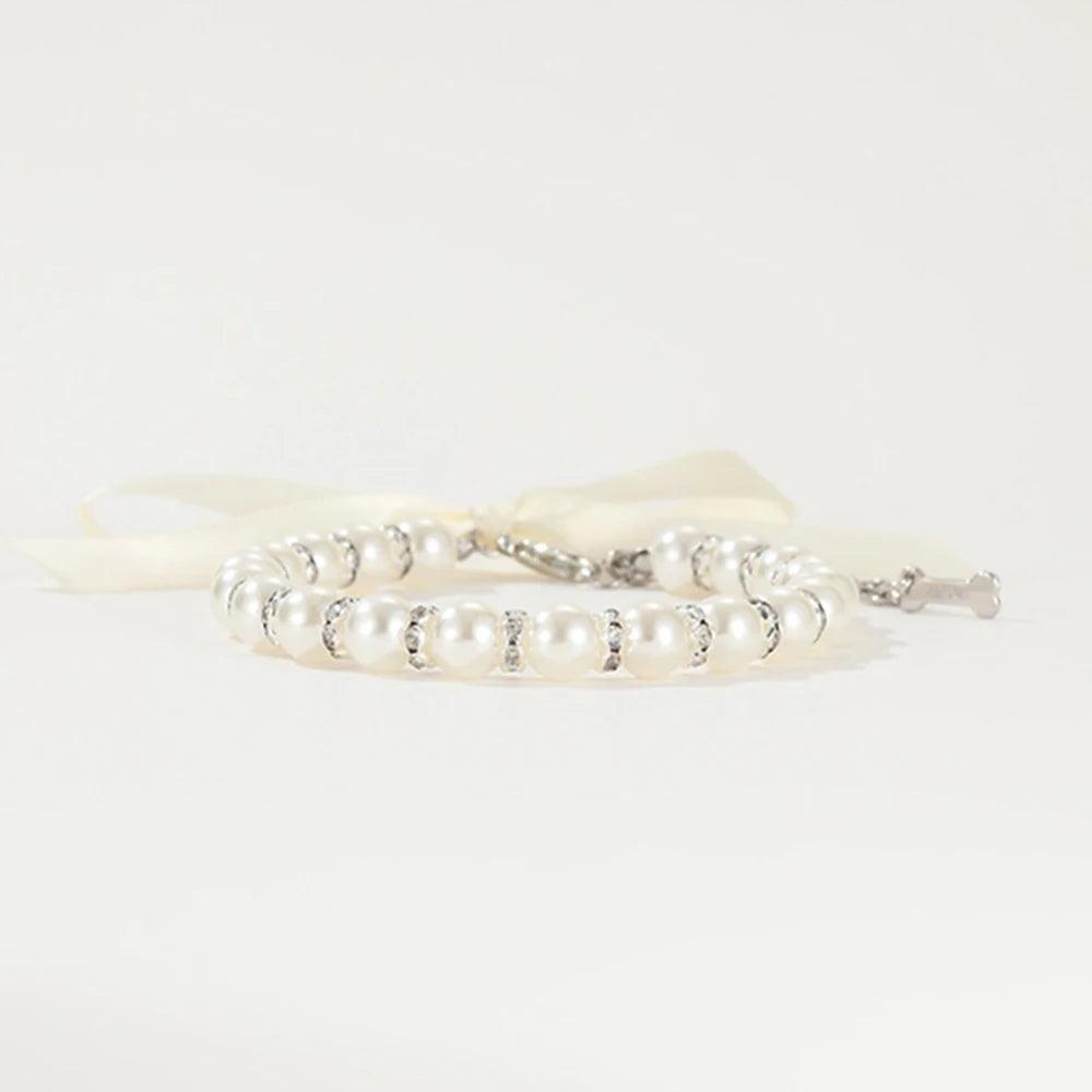 Vue basse de profil d’un collier perlé pour chien avec ruban blanc.
