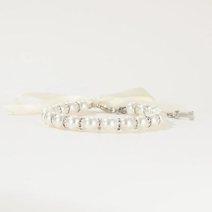Vue basse de profil d’un collier perlé pour chien avec ruban blanc.