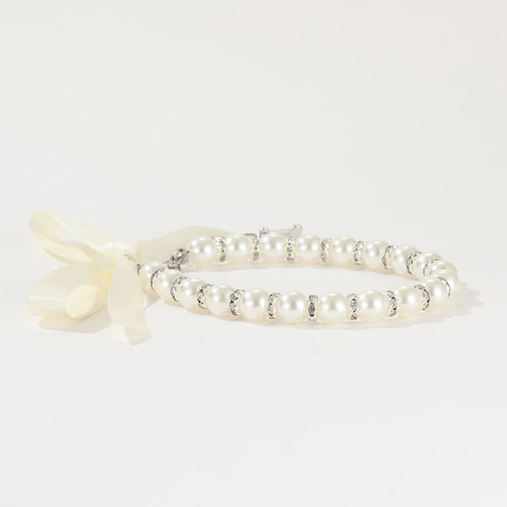 Vue latérale d’un collier perlé pour chien avec nœud ruban blanc.