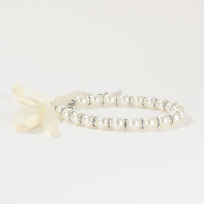 Vue latérale d’un collier perlé pour chien avec nœud ruban blanc.