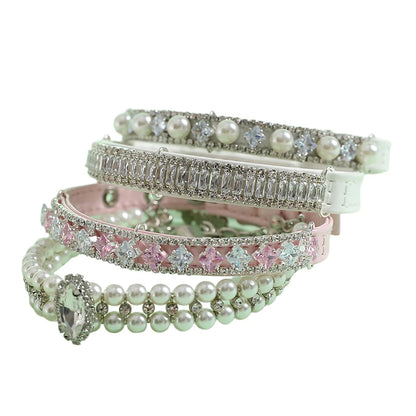 Quatre colliers pour chien empilés, avec modèles à perles, strass et cristaux roses ou blancs.