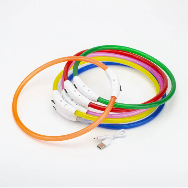 Collection des colliers lumineux pour chien empilés et allumés en différentes couleurs sur fond blanc.