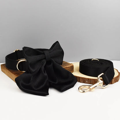 Ensemble collier et laisse pour chien noir avec nœud détachable présenté sur un support en bois.
