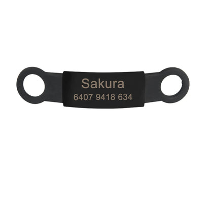Étiquette noire personnalisée pour collier de chien avec gravure visible sur fond clair.