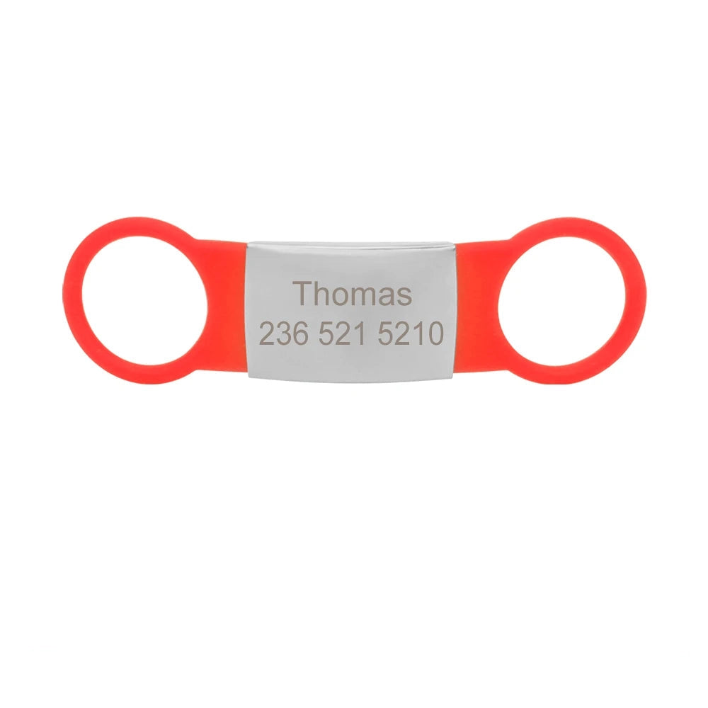 Étiquette rouge pour collier de chien avec plaque argentée gravée Thomas sur fond blanc.