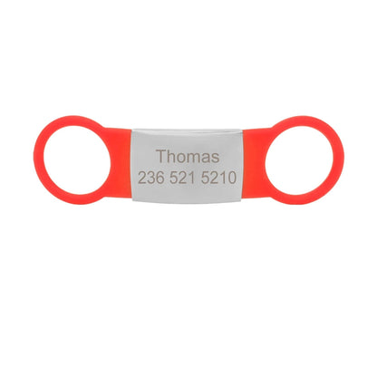 Étiquette rouge pour collier de chien avec plaque argentée gravée Thomas sur fond blanc.