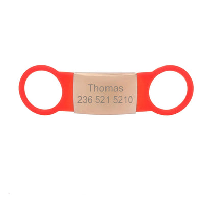 Étiquette rouge pour collier de chien avec plaque bronzée gravée Thomas sur fond blanc.