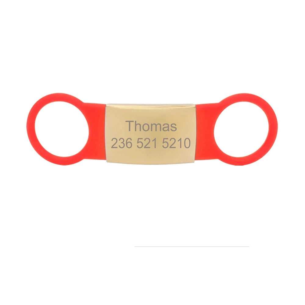 Étiquette rouge pour collier de chien avec plaque dorée gravée Thomas sur fond blanc.