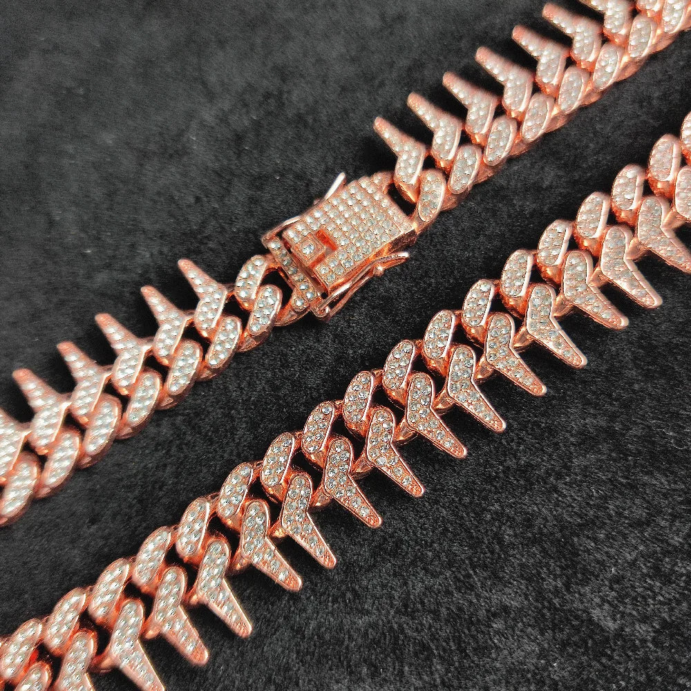 Gros plan d’un collier rose doré pour chien avec strass et pointes sur fond noir.