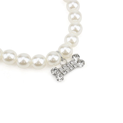 Gros plan sur le pendentif os en strass d’un collier perlé pour chien.