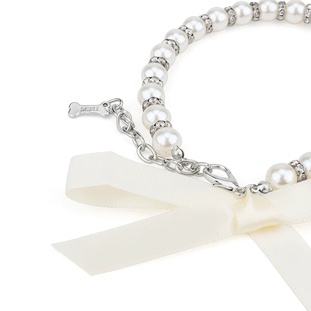 Zoom sur le nœud décoratif d’un collier pour chien en perles blanches.