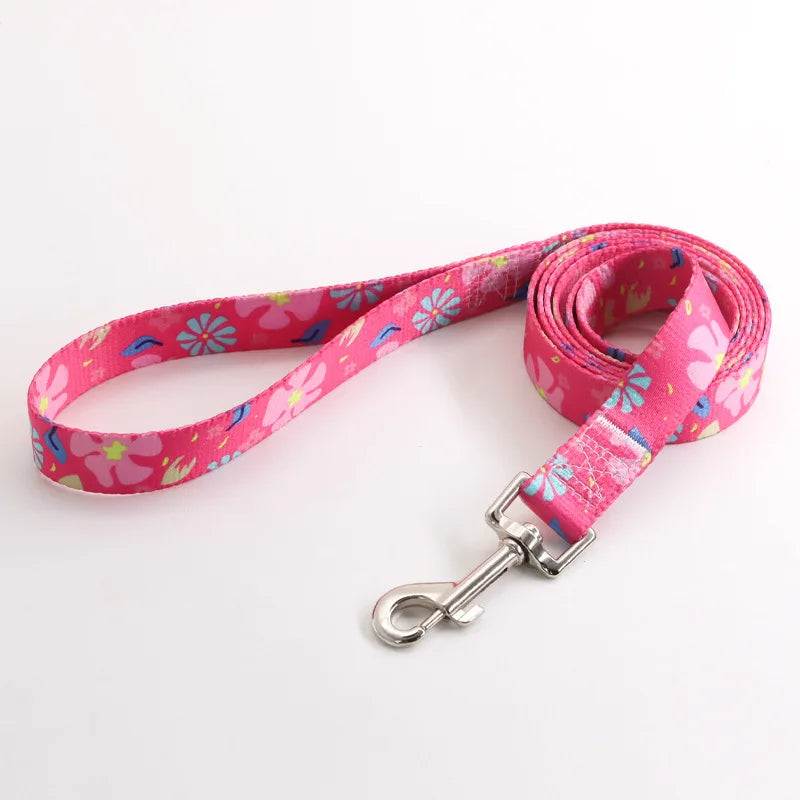 Laisse pour chien en nylon rose avec motifs fleurs multicolores et mousqueton métal argenté sur fond clair.