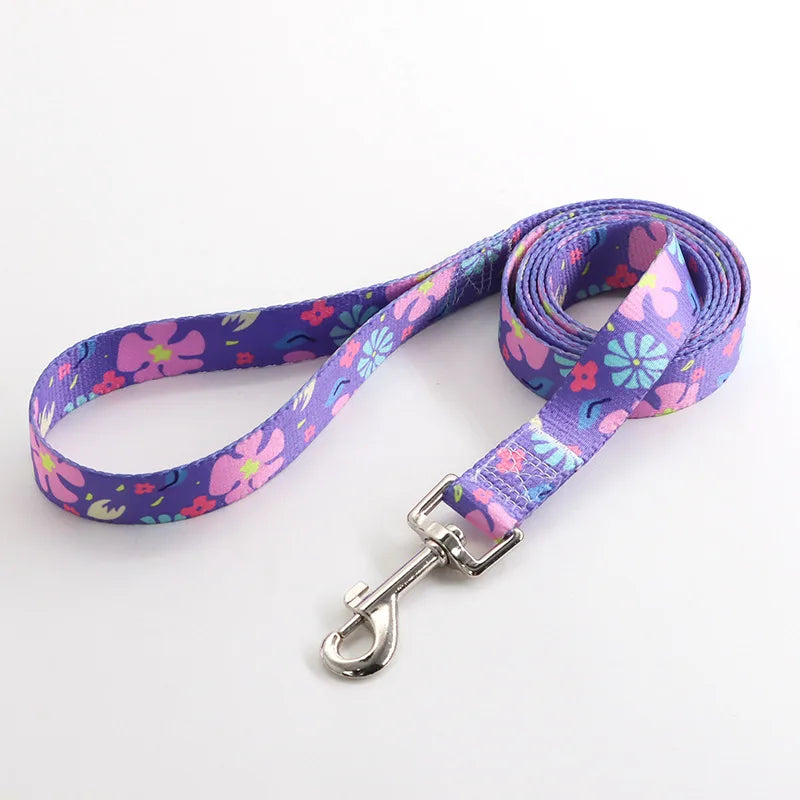 Laisse pour chien en nylon violet avec motifs fleurs roses, bleues et turquoise  et mousqueton métal argenté sur fond clair.