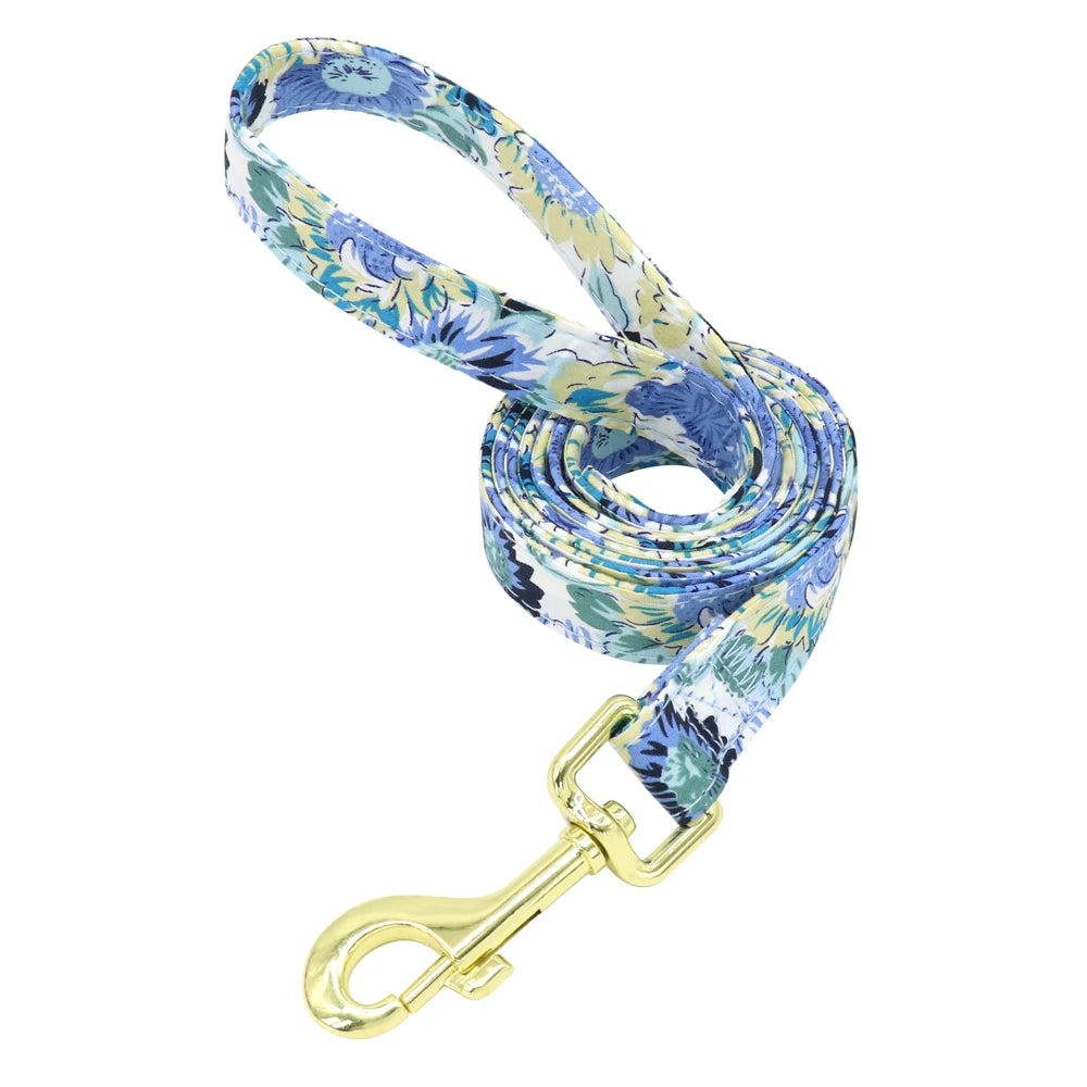 Laisse fleurie bleue pour chien avec mousqueton doré présentée seule sur fond blanc.