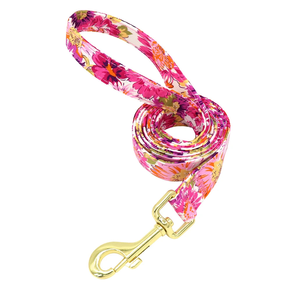 Laisse fleurie rose pour chien avec mousqueton doré présentée seule sur fond blanc.