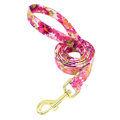 Laisse fleurie rose pour chien avec mousqueton doré présentée seule sur fond blanc.