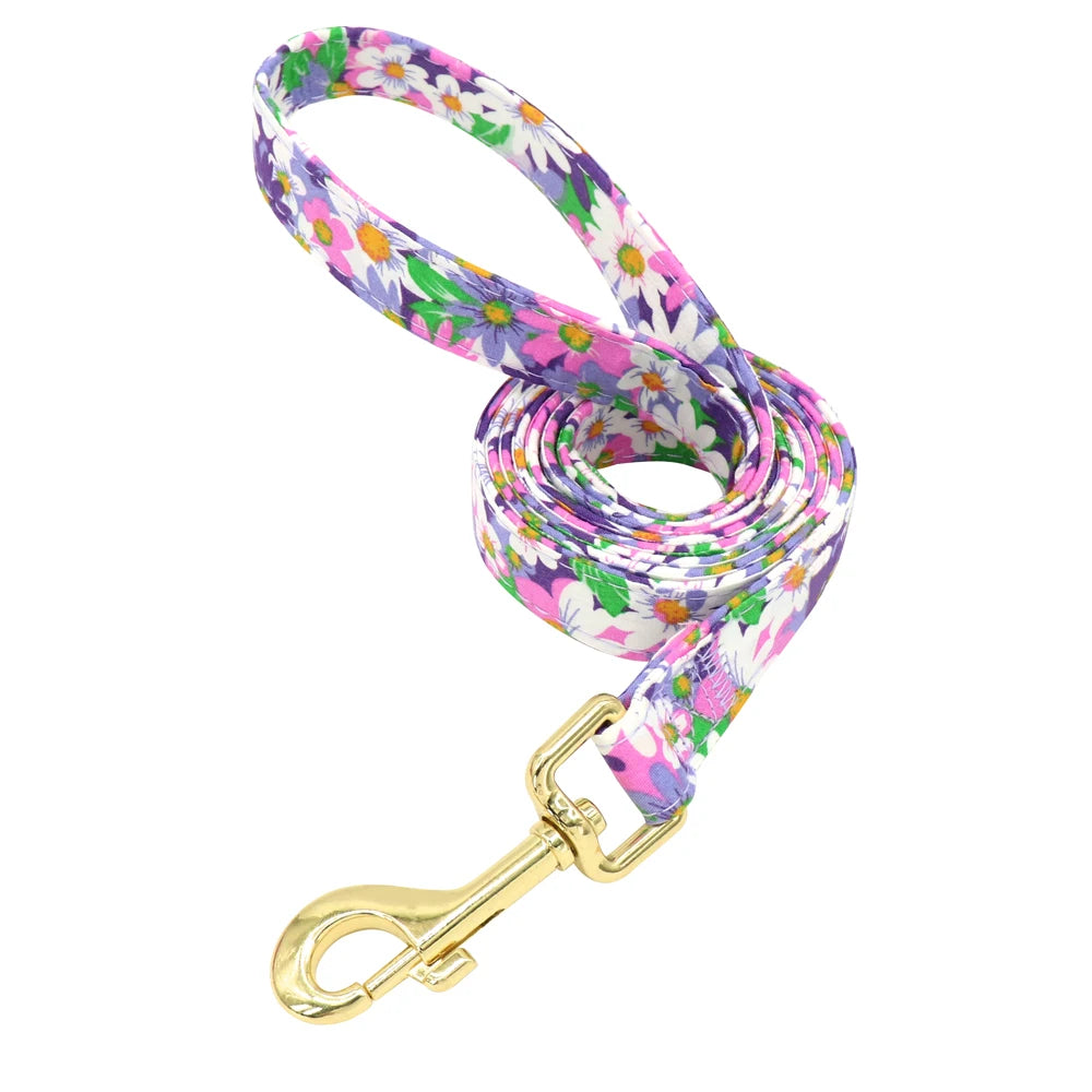 Laisse fleurie violette pour chien avec mousqueton doré présentée seule sur fond blanc.