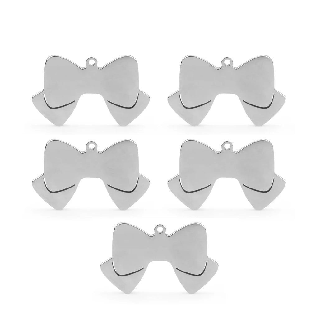 Lot de cinq pendentifs argentés en forme de nœud papillon sur fond blanc.
